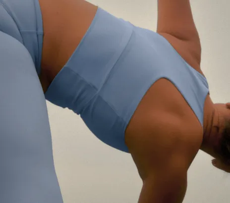 Persona en ropa deportiva azul claro estirándose antes de hacer ejercicio.